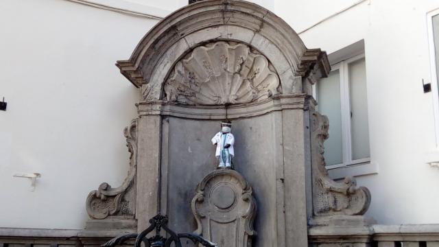 تكريما للأطباء.. تزيين تمثال تاريخه  400 عام بمعطف أبيض وكمامة في بلجيكا
