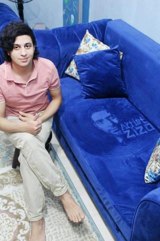 الرسام عبدالعزيز جمال مع رسمته على الأريكة