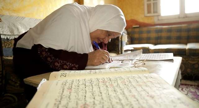 الحاجة سعاد وهي تكتب القرآن الكريم