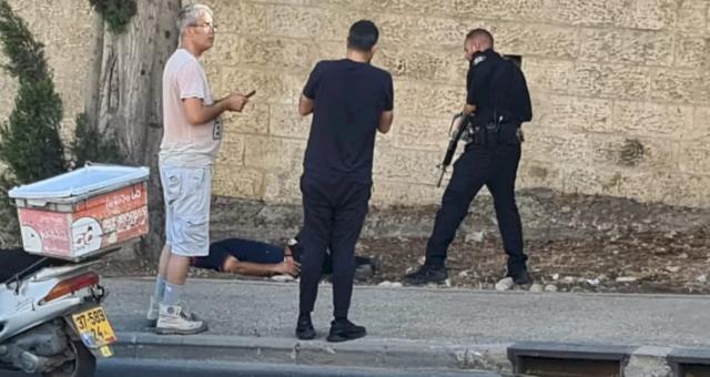 الصحفي الإسرائيلي يرتدي تيشرت وشورت ويقف على رأس الضحية