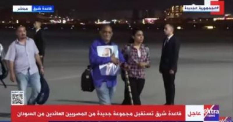 مواطن عائد من السودان يحمل صورة الرئيس السيسي في مطار قاعدة شرق