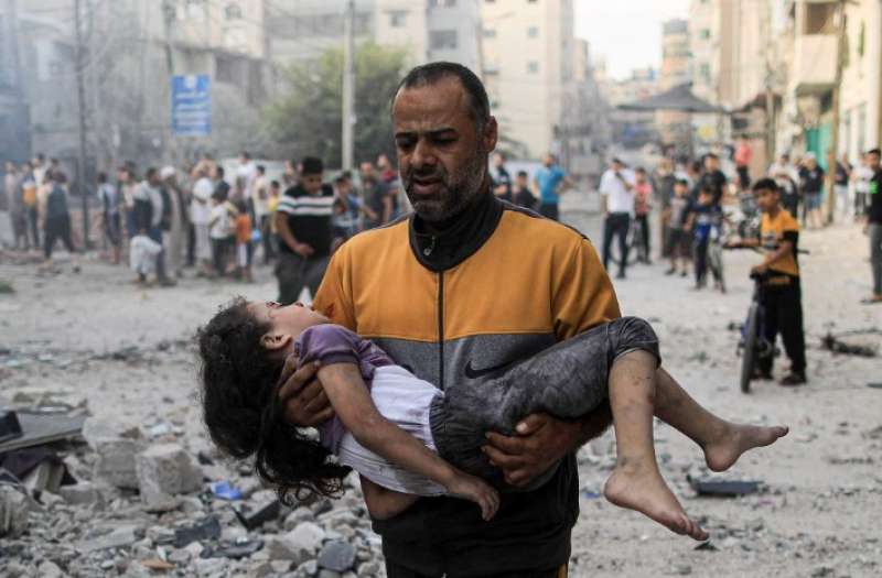 مواطن فلسطيني يحمل طفلة جريحة (وفا)